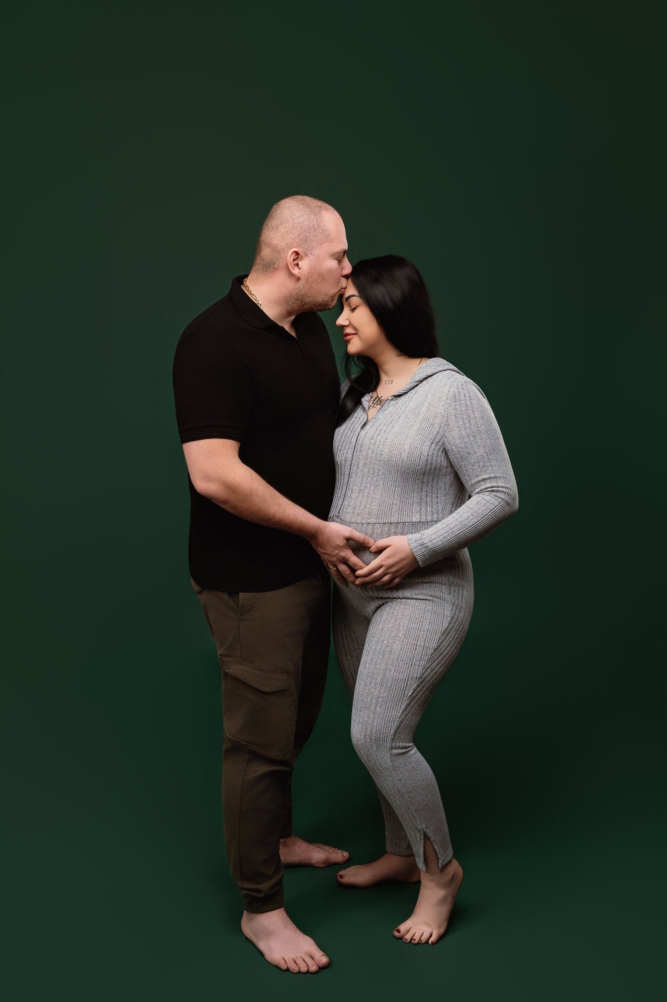 Expecting mother posing with feathered wings and gold sparkle backdrop at maternity photo studio