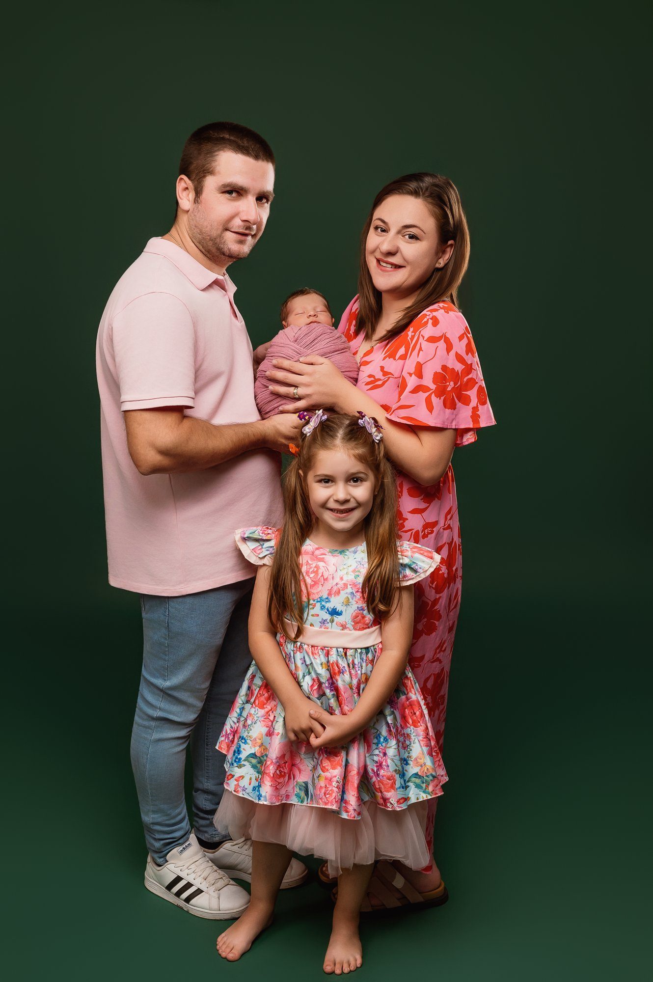 Happy family portrait with parents and two children smiling at green background