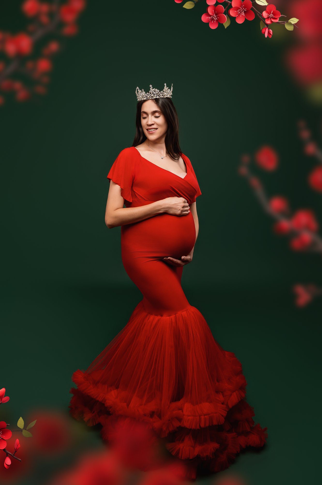 Expecting mother wearing red mermaid dress with tiara surrounded by red flowers against green background