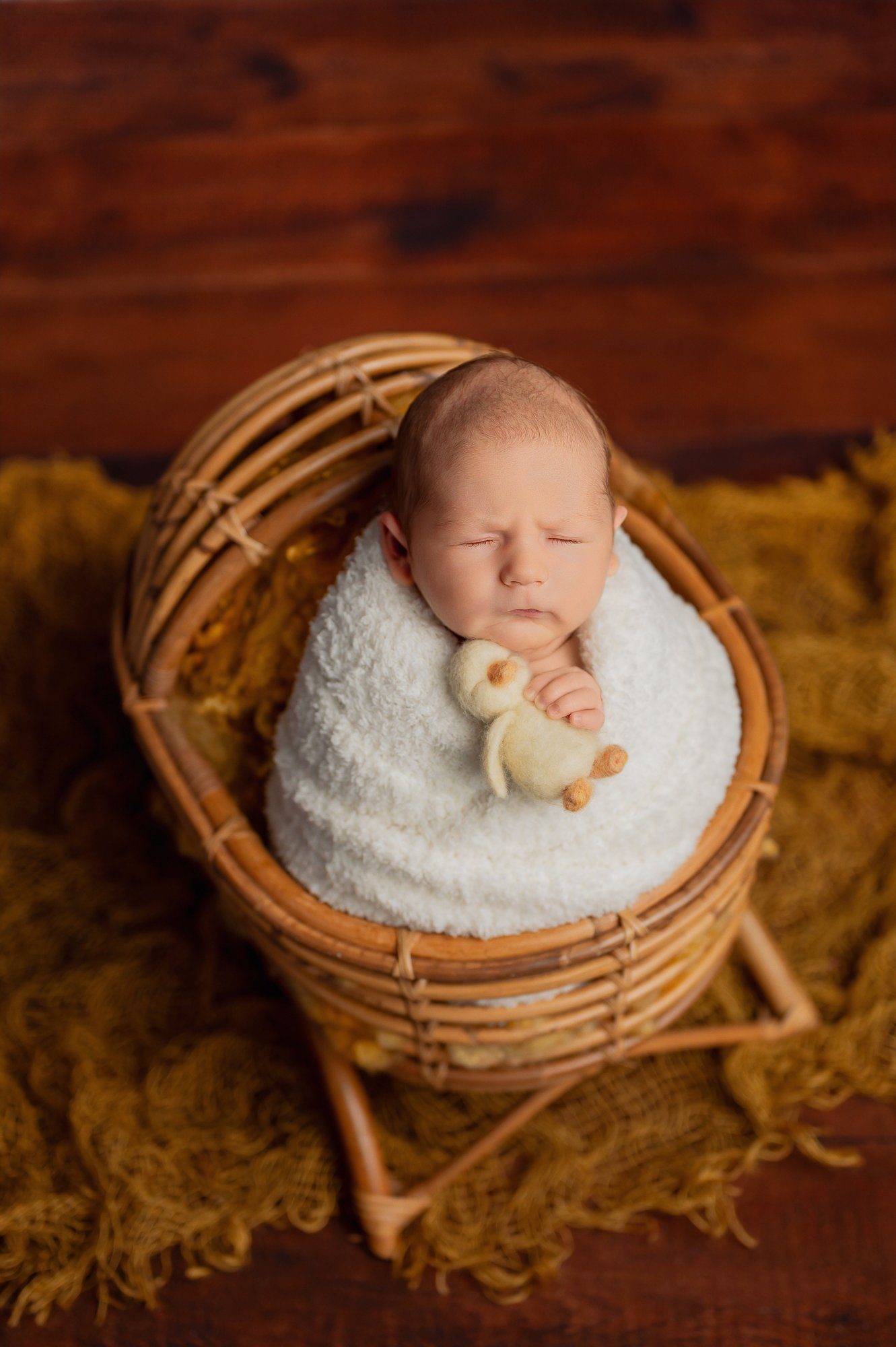 Sibling cuddles with newborn baby in professional studio setting