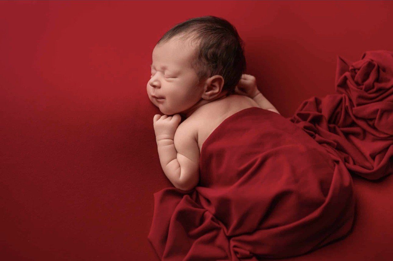 Example: newborn wrapped on red backdrop, Gold package style