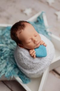 Newborn baby wrapped in white with blue fluffy wool
