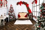 The Elegance Christmas set, red and gold sofa against white panelling with a red bow garland and decorated trees