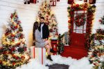 Woman seated on a red bench beside a decorated Christmas tree in the snow