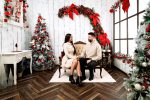 Couple sitting on a white sofa beside a decorated Christmas tree, Christmas photoshoot in Northampton