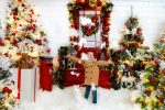 girl in camel coat jumping with arms wide in fake snow by red Christmas door Milton Keynes