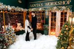 Couple standing outside the Santa's Workshop shopfront in the snow