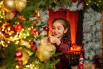 girl in burgundy velvet dress reaching up to decorate Christmas tree Northampton